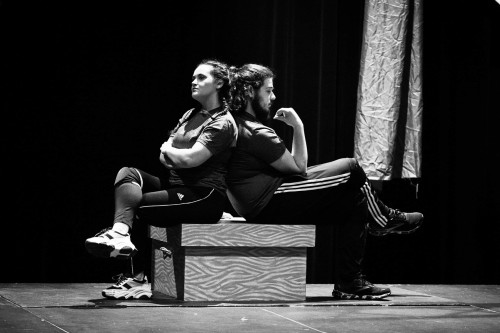 Actors on stage sitting back to back