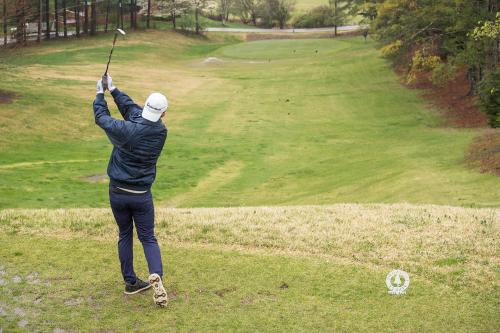 Man hitting golf ball on green