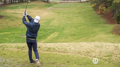Man hitting golf ball on green